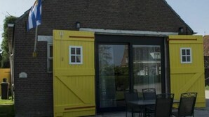 A brick building with a triangular roof, a flag, and a yellow door.
