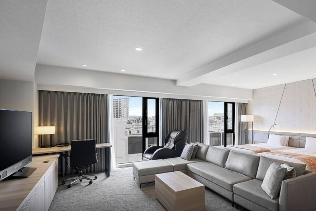 Una habitación de hotel moderna con una cama grande, un sofá, un escritorio y una televisión.