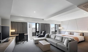 Une chambre d’hôtel moderne équipée d’un canapé, d’un bureau, d’une chaise, d’un lit et d’une télévision.