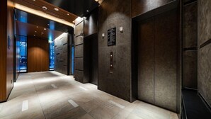 A modern elevator lobby with a polished floor, dark walls, and recessed lighting.