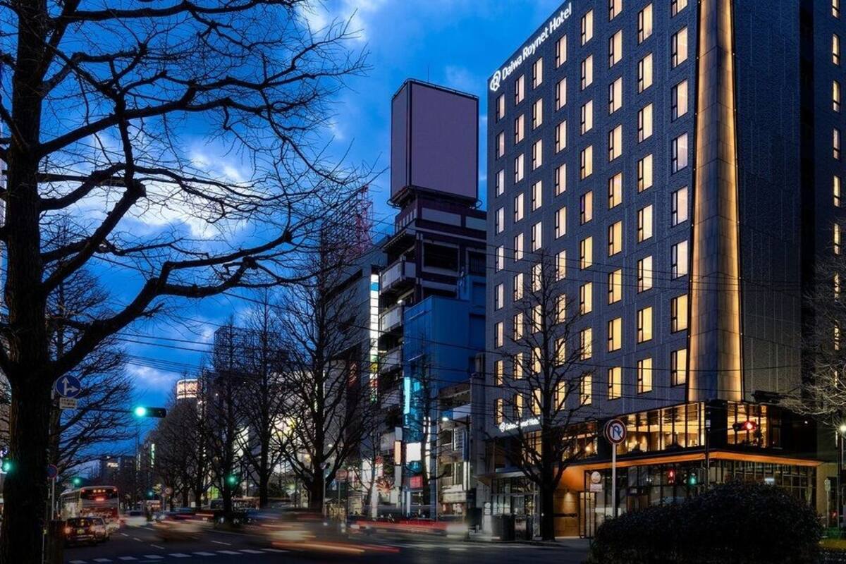 Un moderno edificio de hotel con varios pisos, grandes ventanales y un letrero destacado.