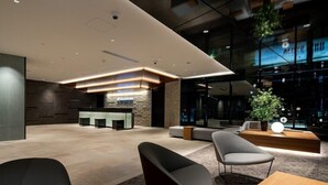 A modern lobby with a reception desk, seating area, and a large window with a view of the city.