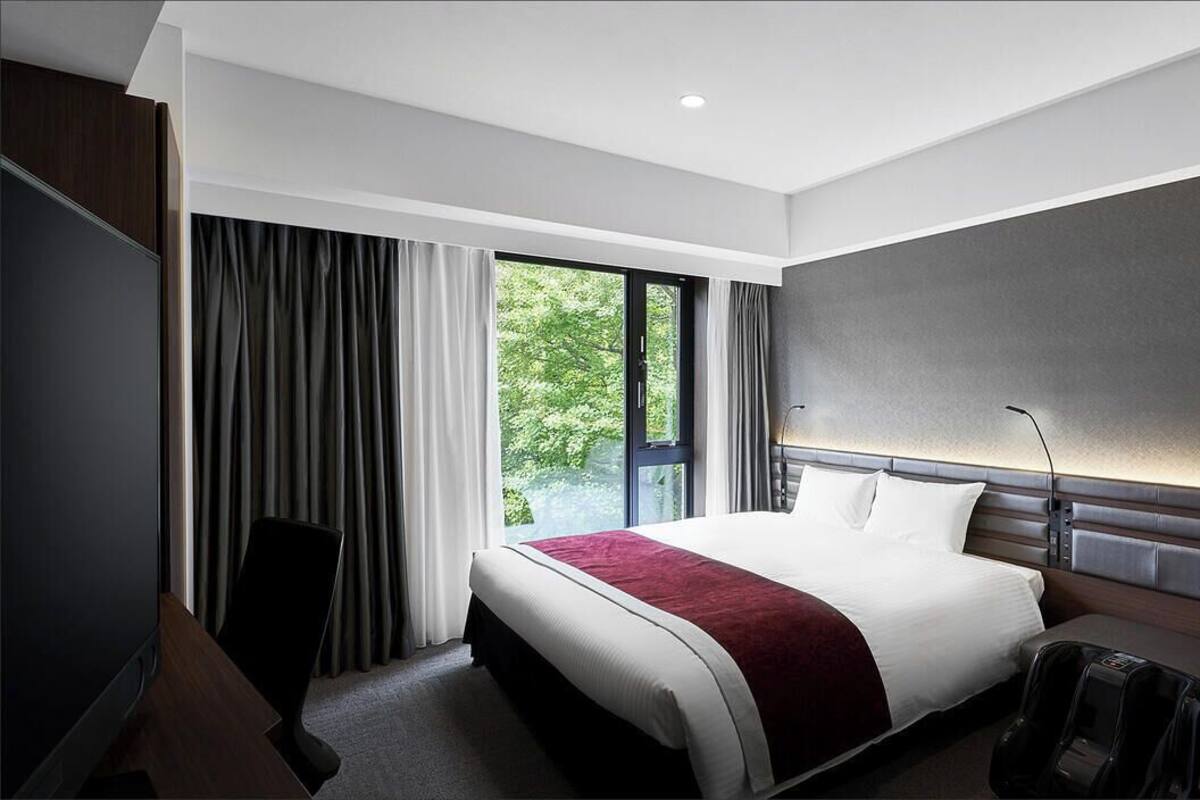 Una habitación de hotel moderna con una cama grande, un escritorio y una silla de masajes.