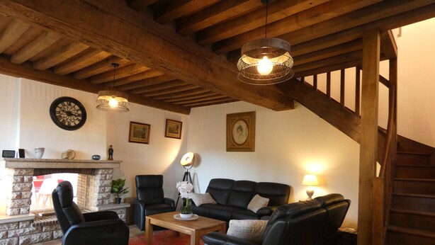 Uma sala de estar aconchegante com lareira, móveis de couro e vigas de madeira.
