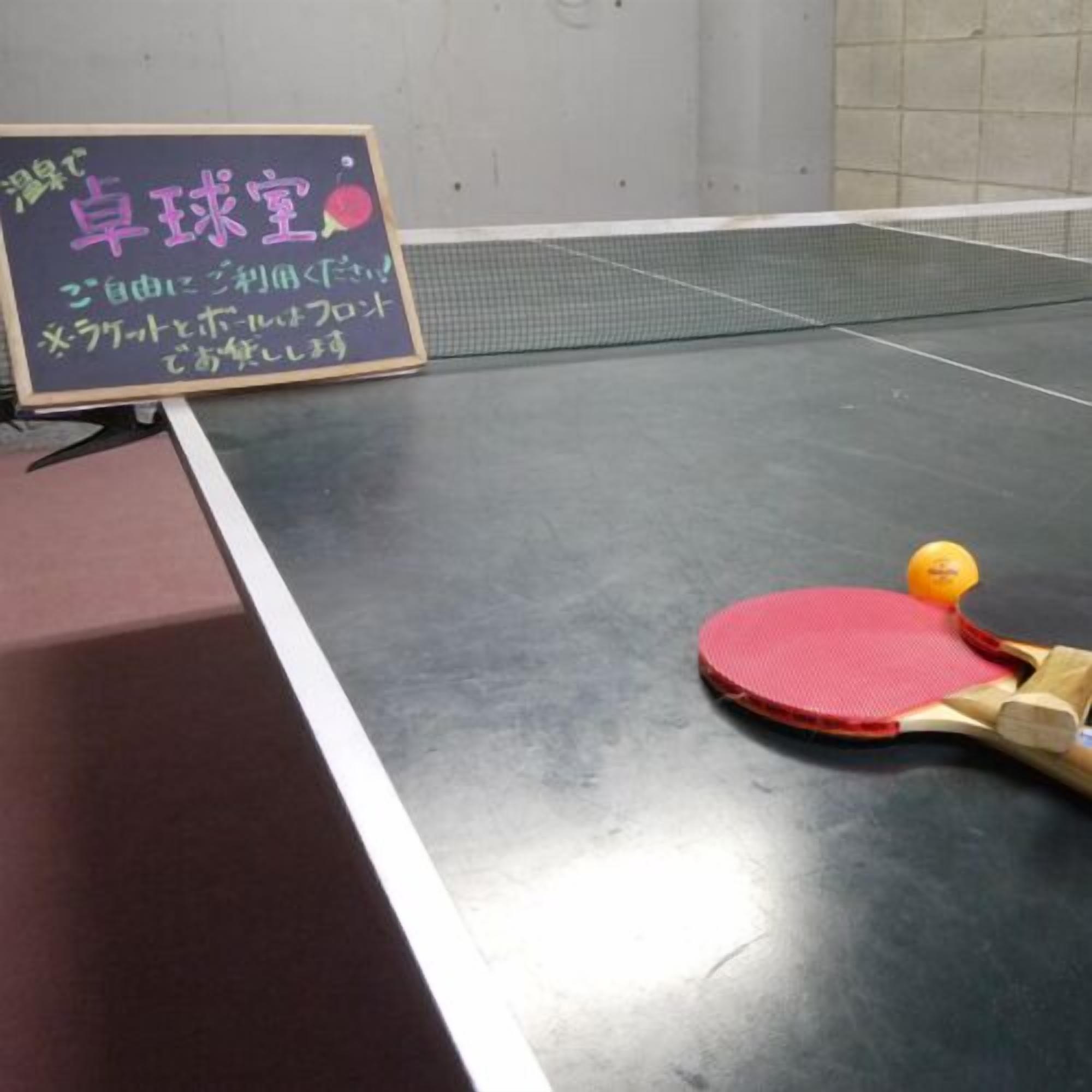 Ett bordtennisbord med ett racket och en boll, samt en skylt med japansk text.