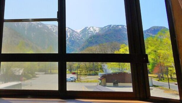 Ein Zimmer mit großem Fenster und Blick auf Berge sowie einen Parkplatz.