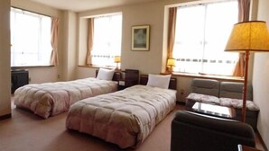 Ein Hotelzimmer mit zwei Betten, einem Sofa, einem Schreibtisch und einer Lampe.