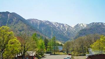 A parking lot with a bus, trees, and mountains in the background.