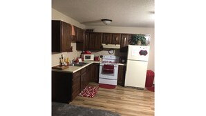 A compact kitchen with wooden cabinets, a microwave, stove, and refrigerator.