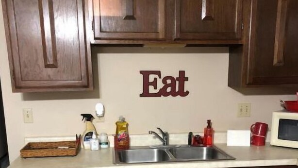 A kitchen with wooden cabinets, a stainless steel sink, and a countertop.