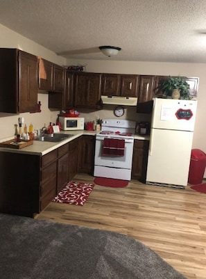 A compact kitchen with wooden cabinets, a microwave, stove, and refrigerator.