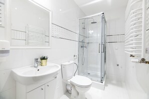 A modern bathroom with a glass-enclosed shower, a white sink, and a toilet. - Dietla 32 Residence (Kraków)