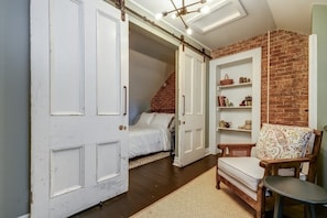 A room with a bed, a chair, a small table, and a brick wall. - From HGTV! Marigold Suite in county farmhouse (Prince Edward)