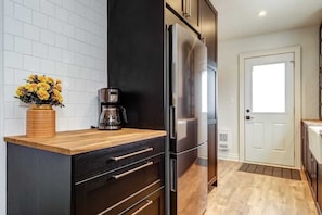 A modern kitchen with a stainless steel refrigerator, wooden countertop, and a coffee maker. - From HGTV! Marigold Suite in county farmhouse (Prince Edward)