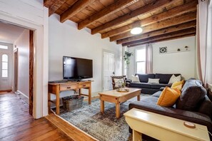 A living room with a wooden ceiling, a TV on a wooden stand, a sofa with cushions, and a coffee table. - The Marigold PEC Family Farmhouse country escape (Prince Edward)