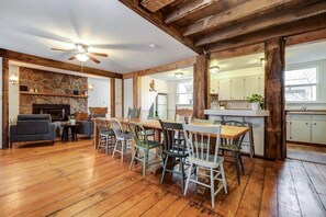 A spacious living room with a fireplace, wooden flooring, and a dining area with chairs and a table. - The Marigold PEC Family Farmhouse country escape (Prince Edward)