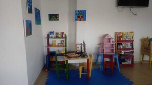 A children's playroom with colorful furniture, a bookshelf, and educational toys. - Tropical Pousada (Guarujá)