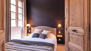 Ein Schlafzimmer mit einem Bett, zwei Nachttischlampen, einem Holzschrank und einem Fenster mit Vorhängen.