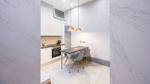 A modern kitchen with a dining table, pendant lights, and a TV mounted on the wall. - Baubo - S. G. Armeno by Napoliapartments (Naples)