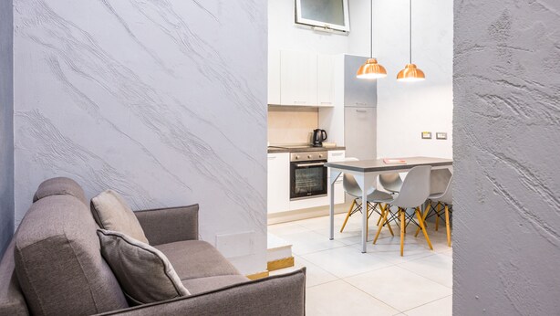 A modern living room with a sofa and a dining area with chairs and a table. - Baubo - S. G. Armeno by Napoliapartments (Naples)