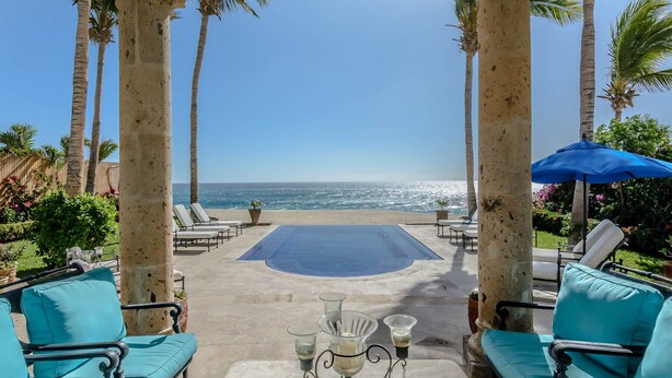 A poolside area with lounge chairs, a pool, and a view of the ocean. - Beachfront 5 BR Villas del Mar 461 fts. Private Pool, Hot Tub, WiFi + Much More! (Los Cabos)