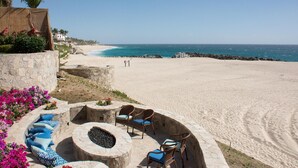A beachside patio with stone seating, a fire pit, and a view of the ocean. - Beachfront 5 BR Villas del Mar 461 fts. Private Pool, Hot Tub, WiFi + Much More! (Los Cabos)