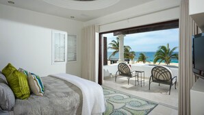 A bedroom with a bed, a view of the beach, and a balcony with chairs. - 2 FREE NIGHTS IN CABO at Villa Pacifica! (Cabo San Lucas)