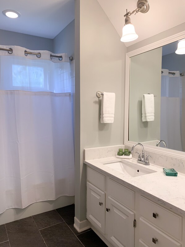 A bathroom with a white vanity, a large mirror, and a shower curtain.