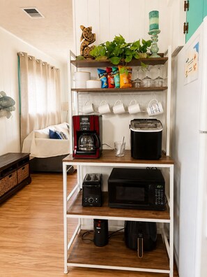 A kitchen with a coffee maker, toaster, microwave, and a shelf with snacks and a plant. - Fore and Aft - Pet-friendly  (Myrtle Beach)