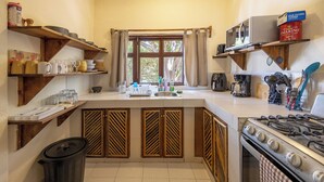 Een compacte keuken met houten kastjes, een gasfornuis, een magnetron en diverse keukengerei.