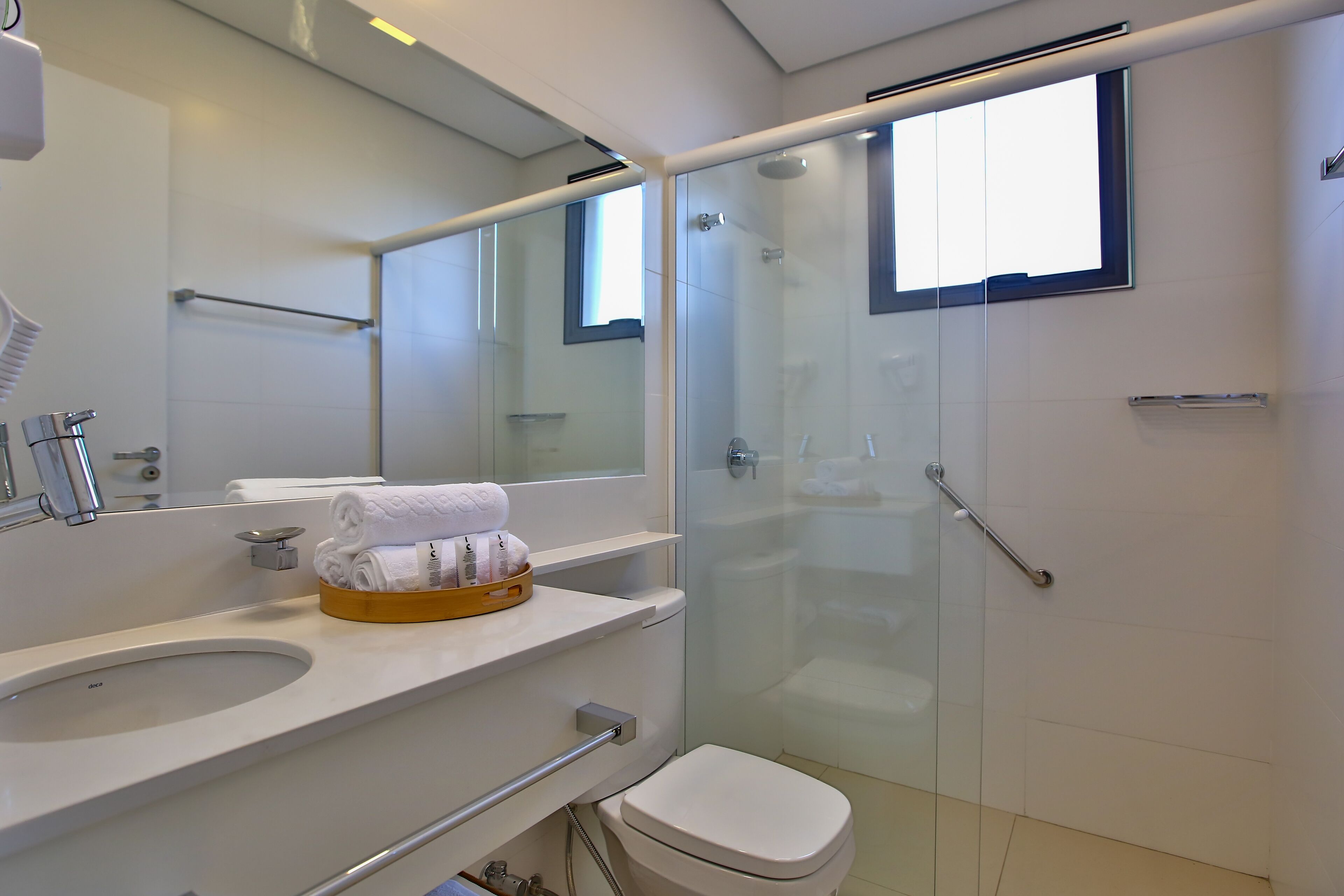 A modern bathroom with a glass-enclosed shower, a white sink, and a toilet.