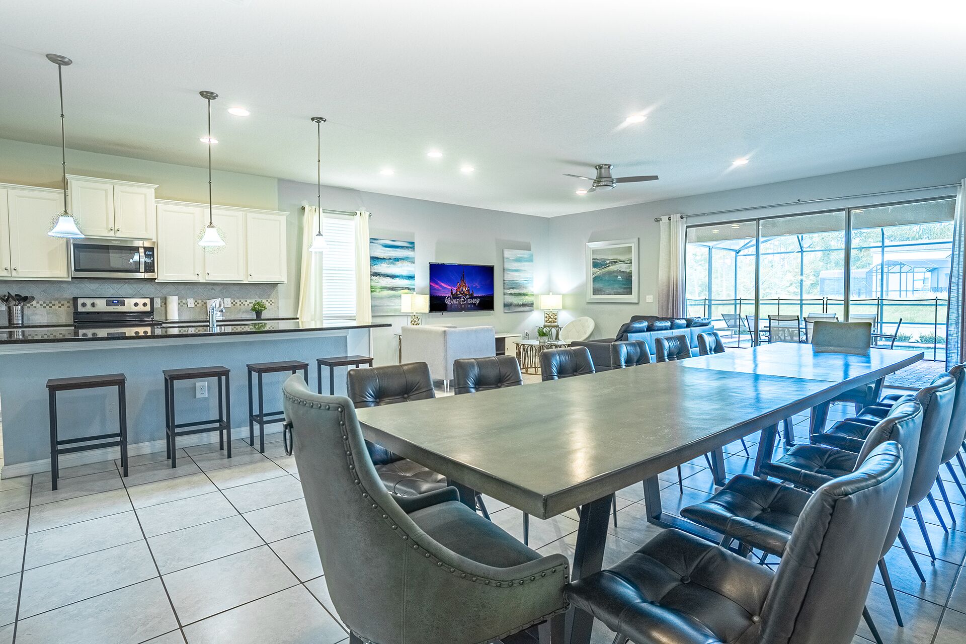 A spacious kitchen with modern appliances, a dining area with leather chairs, and large windows offering a view of the outdoors.