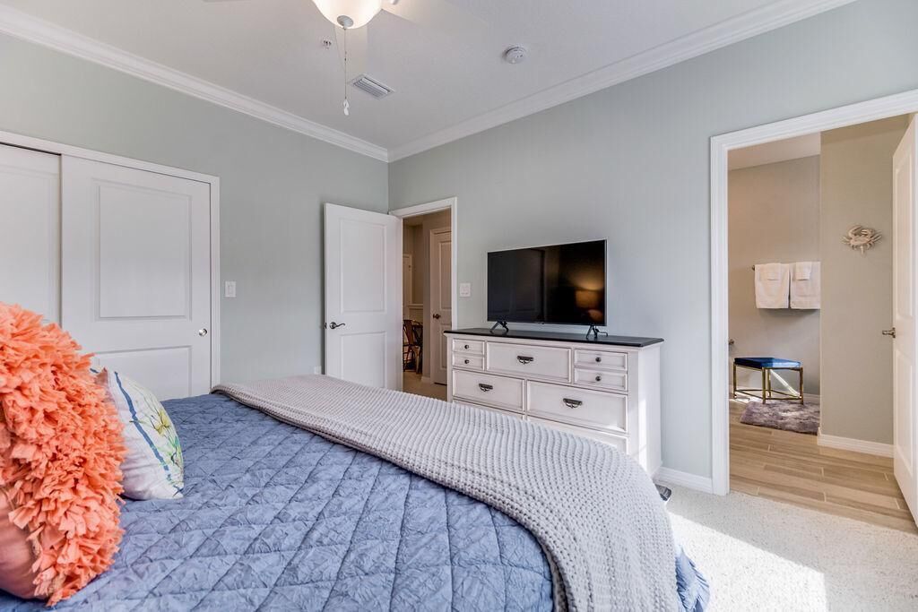 Un dormitorio con cama, cómoda, televisión y armario.