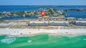 Luftaufnahme eines Küstenhotels mit Strand, klarem türkisblauem Wasser und einer Seebrücke.