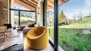A modern living room with a large window, wooden ceiling, and a yellow chair. - NELCOTE - Design and luxury chalet with hot tub (Morzine)