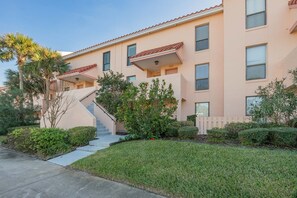 A two-story building with a flat roof, a central staircase, and a well-maintained lawn. - Ocean view townhouse with pools, tennis and so much more! SP 12230 (St. Augustine Beach)