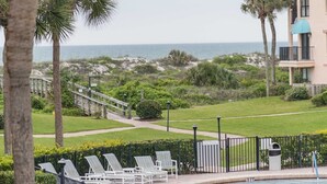 A pool area with lounge chairs, a pathway leading to the beach, and a view of the ocean. - Ocean view townhouse with pools, tennis and so much more! SP 12230 (St. Augustine Beach)