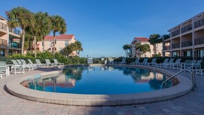A pool surrounded by lounge chairs and palm trees, with a clear blue sky above. - Ocean view townhouse with pools, tennis and so much more! SP 12230 (St. Augustine Beach)