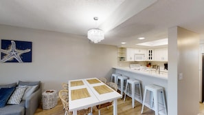 A modern kitchen with white cabinets, a central island with stools, and a dining table with placemats.