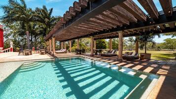 Alberca al aire libre, sombrillas en la alberca y camastros