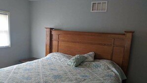 A bedroom with a wooden headboard, a patterned bedspread, and a single pillow. - Cozy camp located in Elk County adjoining state game land. (Byrnedale)