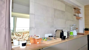 Cozinha moderna com bancada de madeira, cafeteira, liquidificador e um vaso com planta.