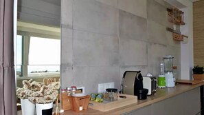 Uma cozinha moderna com uma janela grande, bancada com cafeteira, liquidificador e torradeira.