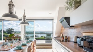 Une cuisine moderne dotée d’un grand îlot central, d’un coin repas offrant une vue agréable et d’un balcon spacieux.