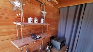 Een houten interieur met planken vol keukengerei, een waterkoker en een klein apparaat.