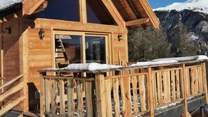 Een houten hut met een balkon en een raam.