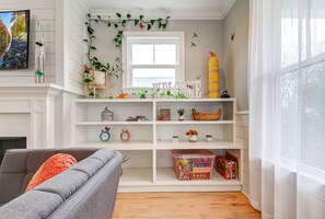 A living room with a fireplace, a grey sofa, a white bookshelf, and a window with a view of the outdoors. - Incline Heights Haven - St Elmo District, Chattanooga (Chattanooga)