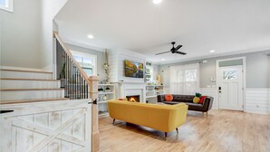 A spacious living room with a yellow sofa, a brown sofa, and a staircase with white railings. - Incline Heights Haven - St Elmo District,  Chattanooga (Chattanooga)
