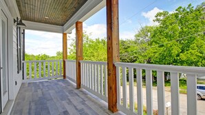A covered porch with wooden beams and white railings, leading to a green landscape. - Incline Heights Haven - St Elmo District,  Chattanooga (Chattanooga)