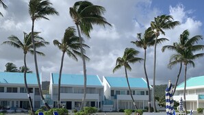 Een resort met een zwembad, palmbomen en een gebouw met een blauw dak.